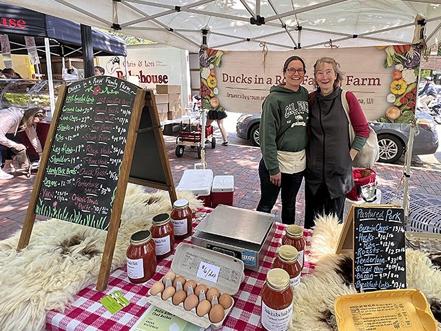 Two women in a farmers' market booth with eggs.